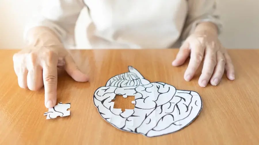 An elderly person touching the last piece of a brain puzzle