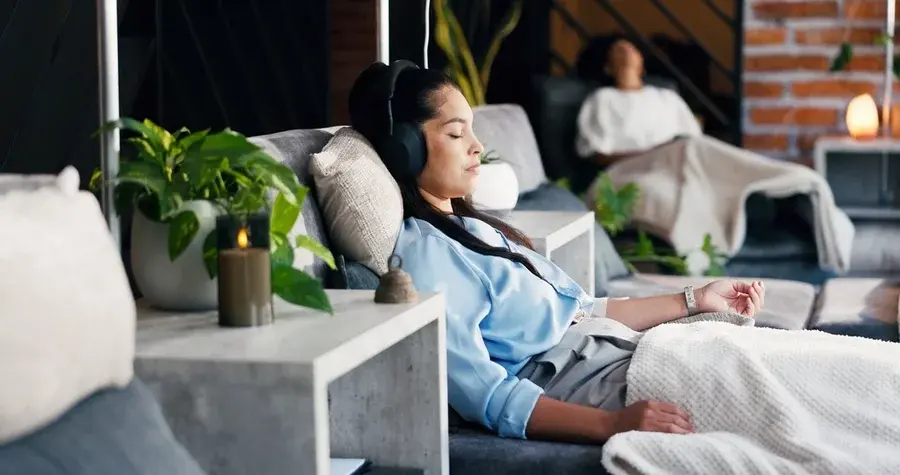 A calm woman, with eyes closed and headphones, having IV therapy.
