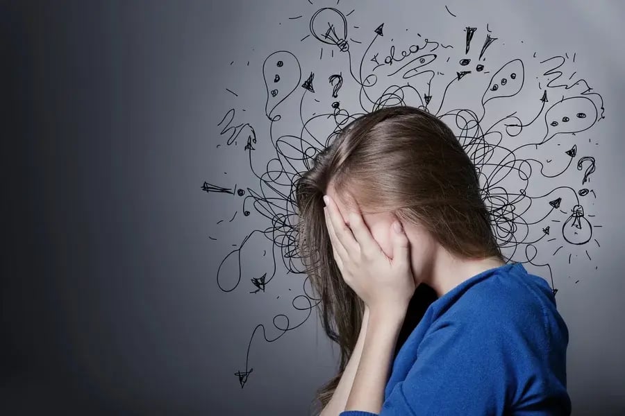 A sad woman with an artistic concept of ADHD and anxiety above her head