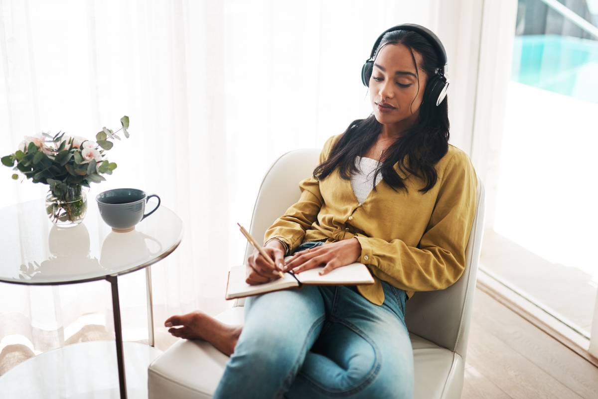 A woman with headphones on journaling